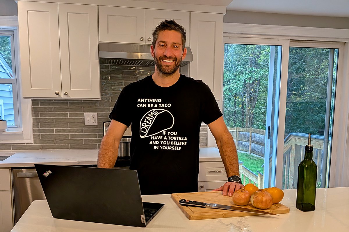 Hans at his kitchen island, laptop open, onions on the cutting board